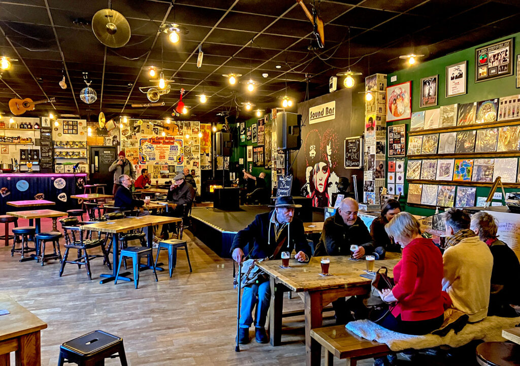 Sound Bar, Skipton: Interior at daytime with tables of customers, stage and LP covers