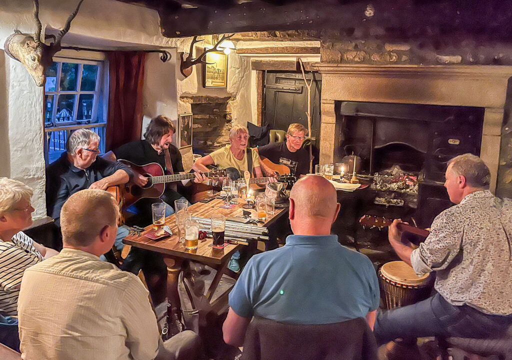Green Dragon, Hardraw: Acoustic session with musicians around a table with fire in background.