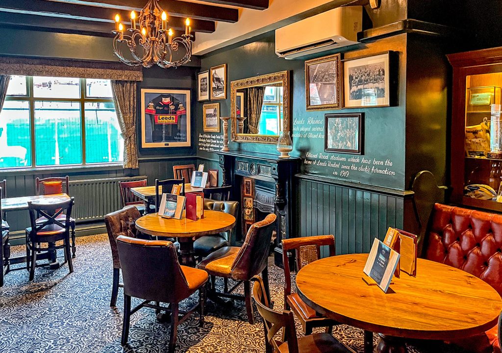 Scarbrough Hotel, Leeds: Left side seating area with patterned carpet, fireplace and pub furniture.