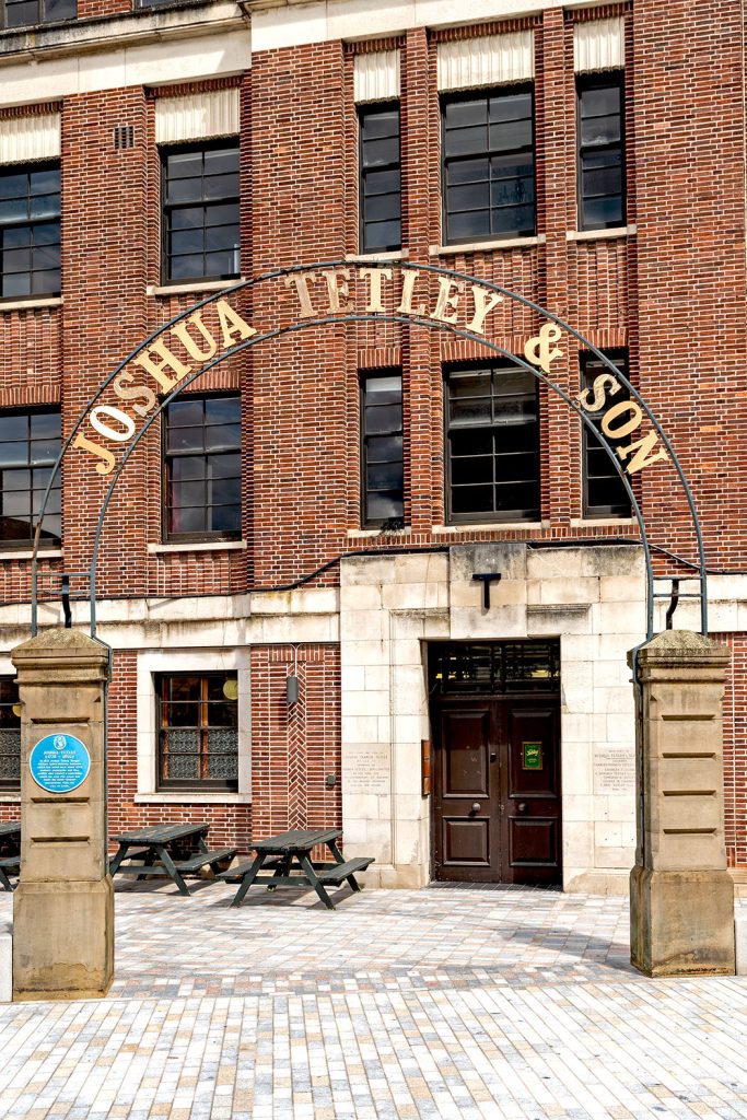 Tetley Pub, Leeds: Old entrance gate with semi-circular 'Joshua Tetley' metal sign on stone pillars.