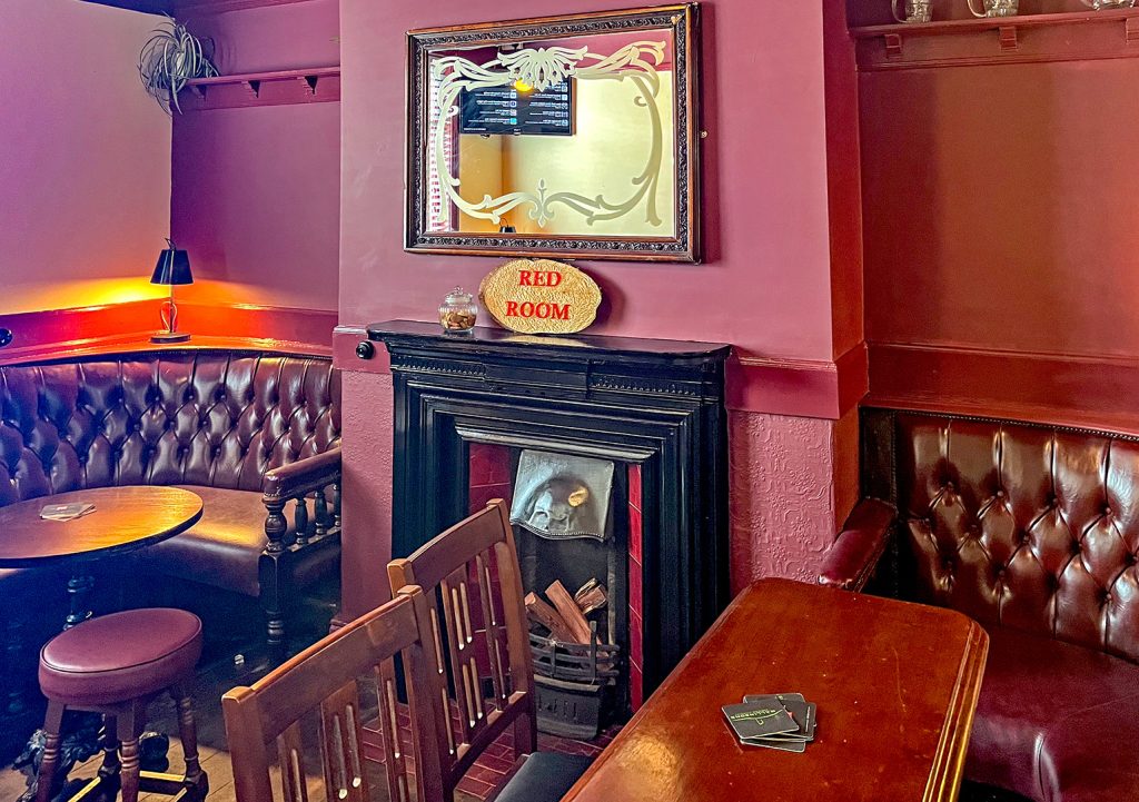 Crown, Stockport: Red Room with maroon upholstered seating, red walls, and fireplace with small mirror above