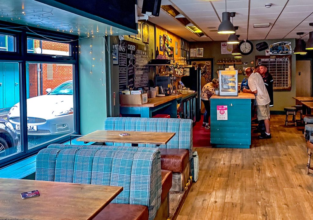 Petersgate Tap, Stockport: Bar with blue fabric seating and customers at bar counter