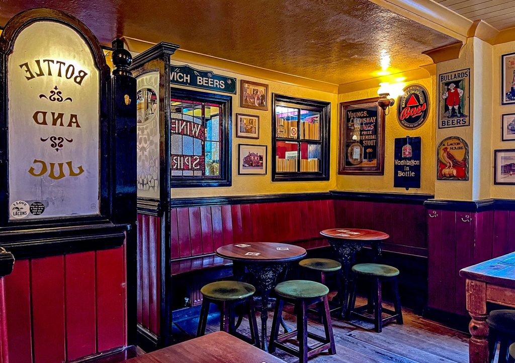 Fat Cat, Norwich: Rear snug with red woooden bench seating and old brewery adverts on wall.