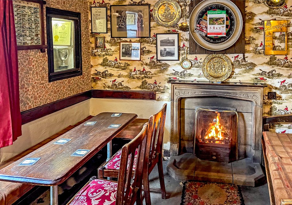 Birch Hall, Beck Hole: The Big Bar showing real in stone fireplace, bench seating and narrow wooden table.