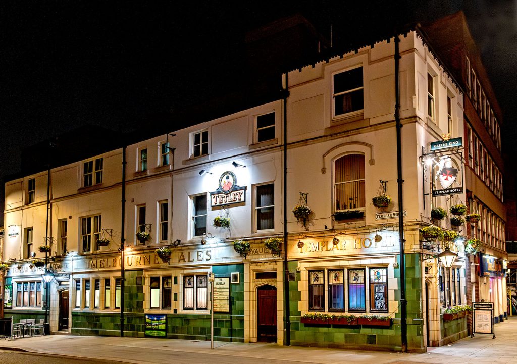Templar, Leeds: Illuminated exterior at night with buff and green tiling with the pub name and ‘Melbourne Ales' lettering.