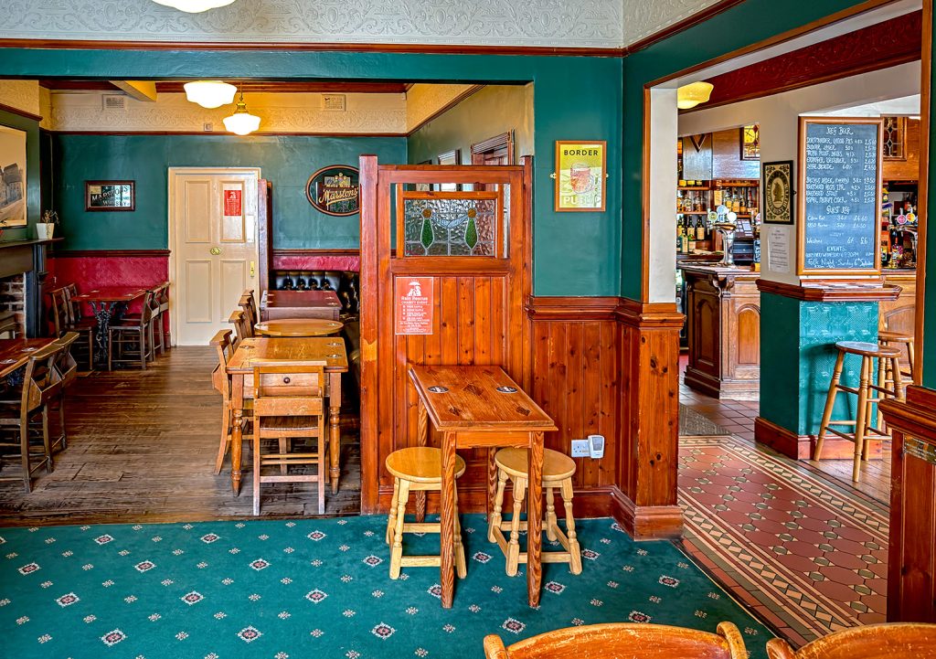 Blake Hotel, Sheffield: Side room with wood and stained glass screen and pub furniture with view through archway to main bar and bar counter.