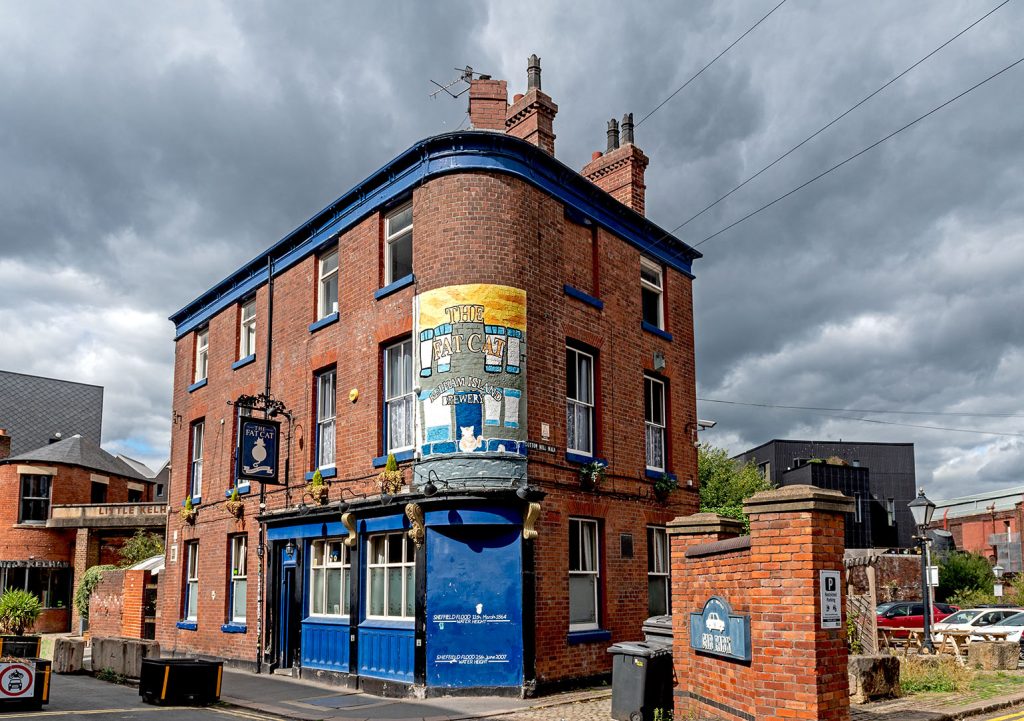 Fat Cat, Sheffield: Red brick corner pub with blue frontage and fading painted mural on corner with pub name and 'Kelham Island Brewery' lettering.