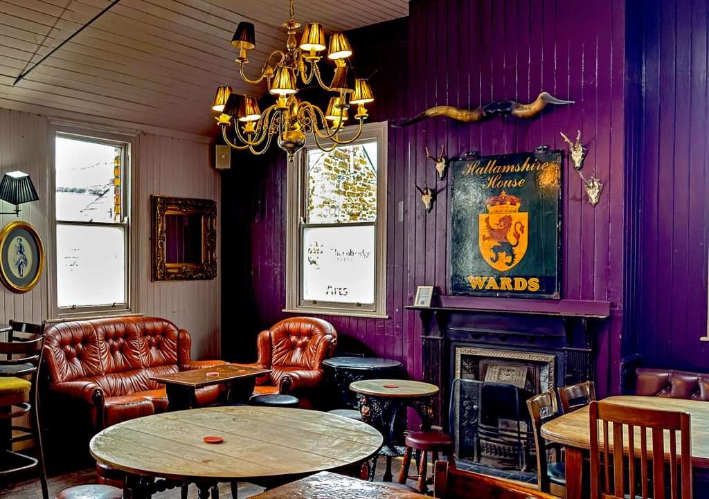 Hallamshire House, Sheffield: Rear lounge with old pub sign, purple walls and pub furniture.