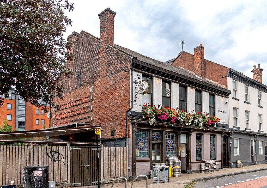Riverside, Sheffield: White and mauve front exterior and red brick side wall with red neon sign.